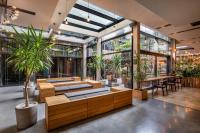 a lobby with tables and potted plants and windows at IOTA Hotel Tbilisi in Tbilisi City