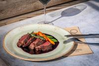 a plate of meat and vegetables with a glass of wine at IOTA Hotel Tbilisi in Tbilisi City