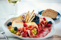 een bord met vlees en fruit en een glas wijn bij Prim&Proper in Porto