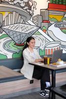 a woman sitting at a table with a laptop at Amaris Hotel Kalimalang in Jakarta