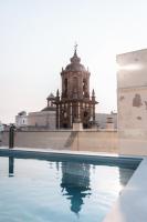 a building with a clock tower next to a swimming pool at Boutique Hotel OLOM - Only Adults recommended in Cádiz