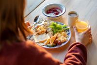 una donna seduta a un tavolo con un piatto di cibo di Ski-Inn Kultakero a Pyhätunturi