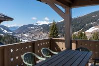 a wooden table and chairs on a balcony with mountains at Chalet Le Lapye in Les Gets