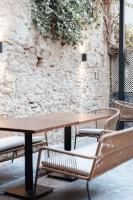 a wooden table and chairs in front of a stone wall at Boutique Hotel OLOM - Only Adults recommended in Cádiz