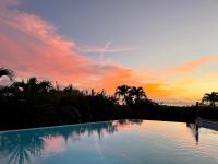 a swimming pool with a sunset in the background at Villa Libellule in Grand-Bourg