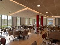 Un comedor con mesas y sillas y ventanas. en Domitys Les Cépages, en Gaillac