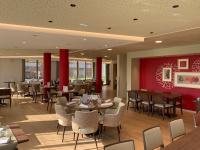 un restaurante con mesas y sillas y una pared roja en Domitys Les Cépages, en Gaillac