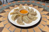Un plato de albóndigas con salsa para mojar sobre una mesa en Alobar1000 Hostel, en Katmandú