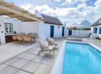 a patio with a swimming pool and a table and chairs at Seagulls Nest in Struisbaai