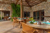 a patio with tables and chairs and a stone wall at Villa Pantai Milagres Exclusive Hotel in São Miguel dos Milagres