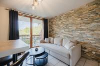 a living room with a couch and a brick wall at Bel appartement 6 couchages au plan d&#39;eau d&#39;Embrun in Embrun
