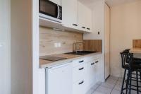 a kitchen with white cabinets and a sink and a microwave at Bel appartement 6 couchages au plan d&#39;eau d&#39;Embrun in Embrun