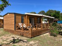 une cabane en bois avec une véranda et une clôture dans l&#39;établissement Camping RCN Domaine de la Noguière, au Muy