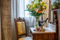 a vase of flowers on a table next to a chair at Palazzo Bembo - Exclusive Accommodation in Venice