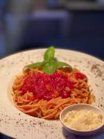 een bord pasta met saus en een kommetje kaas bij San Antonio Beach Guesthouse & Restaurant in Kata Beach