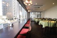 Un comedor con mesas y sillas y grandes ventanales. en Hotel Green Line, en Sendai