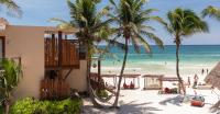 Un edificio en la playa con palmeras y el océano. en La Zebra Tulum, a Small Luxury Hotel, en Tulum
