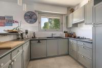 a kitchen with white cabinets and a clock on the wall at Deconnexion et detente sur la Presqu ile de Rhuys in Le Tour-du-Parc