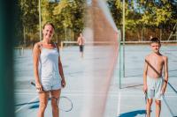 a woman and a boy standing on a tennis court at Camping Sunêlia la Clémentine in Cendras