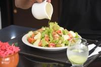 Eine Person, die eine Flasche Milch über einen Salat gießt in der Unterkunft Mercure Recife Navegantes in Recife