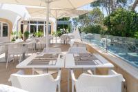 un ristorante con tavoli e sedie bianchi su un balcone di Alcanada Golf Hotel a Port d'Alcudia