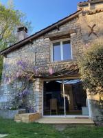 a stone house with a window and purple flowers at Le Clos des Grands Frênes in Pons