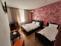 Cette petite chambre comprend deux lits et une table. dans l&#39;établissement Hotel Jiul, à Eforie Sud
