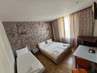 Cette chambre comprend deux lits, une table et un bureau. dans l&#39;établissement Hotel Jiul, à Eforie Sud