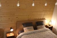 a bedroom with a wooden wall with a bed and lights at Le petit Gambetta in Belfort