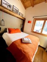 a bedroom with a bed with an orange blanket and a window at Appartement dans chalet de luxe Megève in Megève