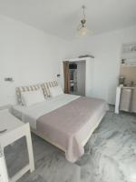 a white bedroom with a large bed and a table at Theofanis Studios in Agia Anna Naxos