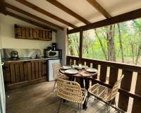a kitchen with a table and chairs on a balcony at Camping Sunêlia la Clémentine in Cendras