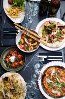 a table topped with plates of pizza and pasta at La Métairie De Terrefort in Bouliac