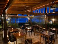 a restaurant with wooden tables and chairs with a view at Villa Sapê Pousada in Ubatuba