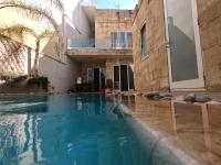 a swimming pool in front of a house at The Luxury Home - Next to airport! in Kirkop