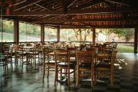 a row of wooden chairs and tables in a restaurant at Engenho da Serra Hotel EcoResort in Capitólio