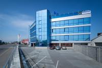 a large glass building with two cars parked in a parking lot at OC Panorama in Velké Meziříčí