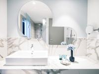 a white bathroom with a sink and a mirror at Falkensteiner Family Hotel Diadora in Zadar