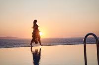 a woman walking on the beach at sunset at Ubud Mykonos in Agios Ioannis Mykonos