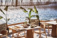 a table and chairs on a patio next to the water at Ubud Mykonos in Agios Ioannis Mykonos