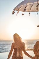a woman walking on the beach with an umbrella at Ubud Mykonos in Agios Ioannis Mykonos