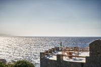 a patio with tables and chairs on the water at Ubud Mykonos in Agios Ioannis Mykonos