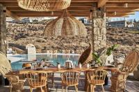 a wooden table and chairs in a restaurant with a pool at Ubud Mykonos in Agios Ioannis Mykonos