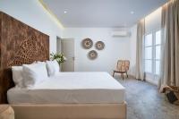 a bedroom with a large white bed and a chair at Ubud Mykonos in Agios Ioannis Mykonos