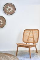 a rattan chair and a table in front of a wall at Ubud Mykonos in Agios Ioannis Mykonos