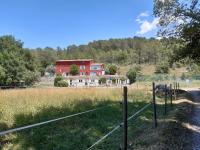 a fence in a field with a red house at La ferme de Manon in Montferrat