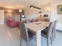 a dining room and living room with a wooden table and chairs at Apartment Zeebries by Interhome in Bredene