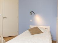 a bedroom with a white bed with a lamp on the wall at Apartment Plasenn by Interhome in Saint Malo