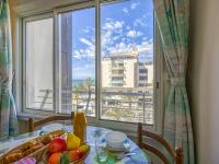 a table with a plate of fruit and a view of a city at Apartment Le Sunset-Cap Sud-23 by Interhome in Cap d&#39;Agde