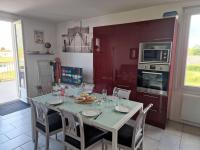 a kitchen with a dining table with chairs and a kitchen with at Charmant duplex à 500 m de la plage in Barbâtre